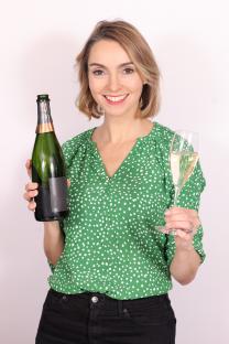 Woman holding a bottle and glass of champagne.
