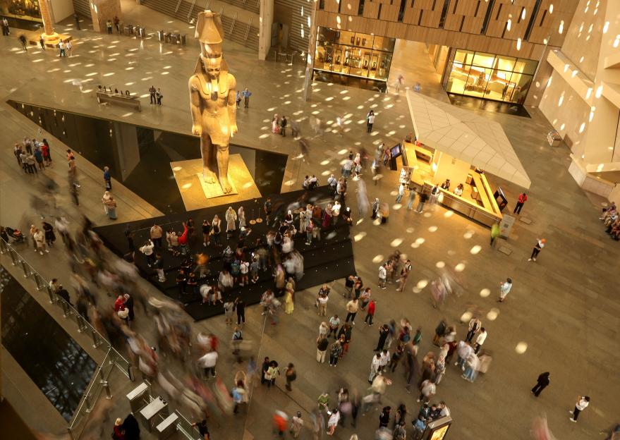 Visitors in front of a statue of King Ramses II at the entrance of the Grand Egyptian Museum in Giza