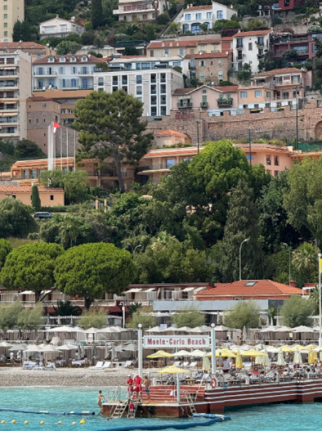 Monte-Carlo Beach with people relaxing on the beach and a floating platform.