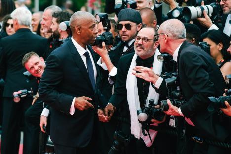 Denzel Washington on the red carpet at the Cannes Film Festival, surrounded by photographers.