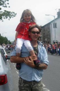 A father carrying his young daughter on his shoulders.