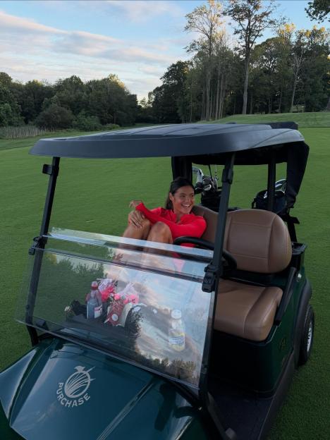 Woman smiling in golf cart on course.