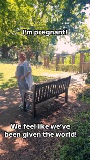 Pregnant woman standing in a park, announcing her pregnancy.