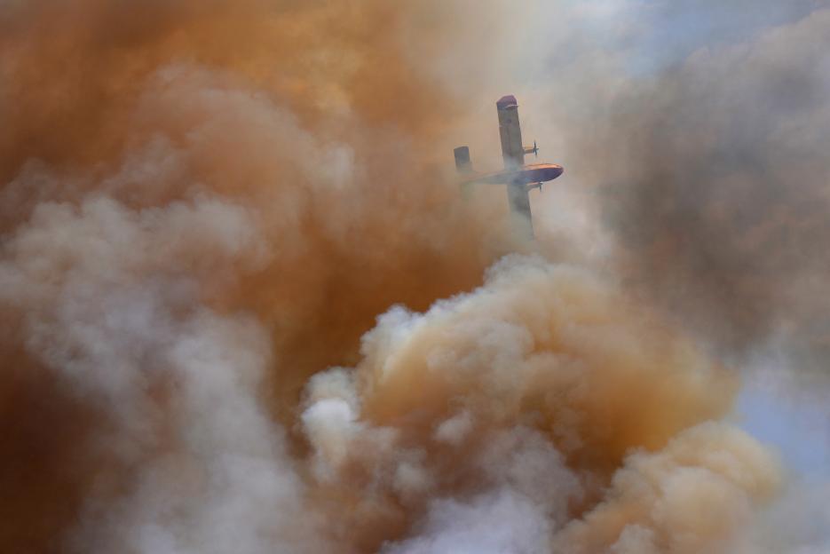 Firefighting plane above wildfire smoke.
