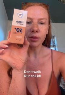 Woman holding up a bottle of Cien tinted facial fluid SPF 50+.