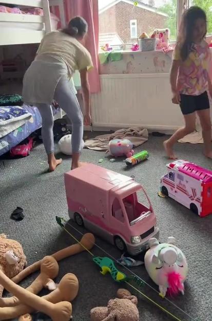A woman and two children cleaning up a messy bedroom.