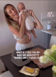 Woman holding a baby, with a potty training seat and wipes on a table.