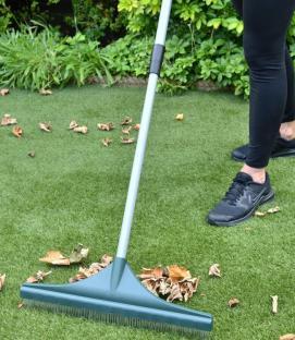 Person using a telescopic artificial grass rake.