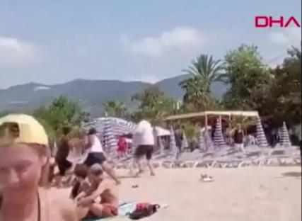 A person being attacked on a busy beach.
