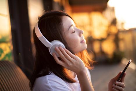 Young woman listening to music with headphones and holding a smartphone.