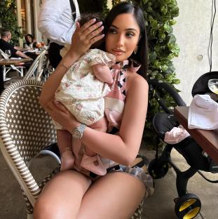 Woman holding a baby at an outdoor restaurant.