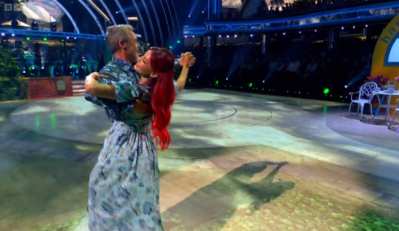 A man and woman ballroom dancing on a stage.
