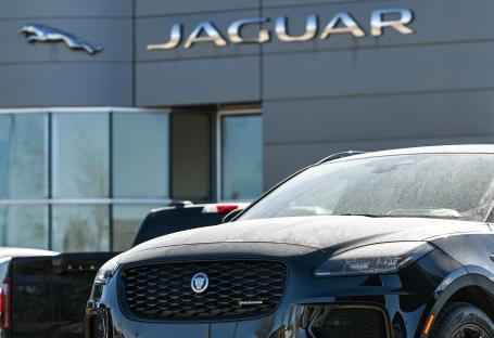 Black Jaguar parked in front of a Jaguar dealership.