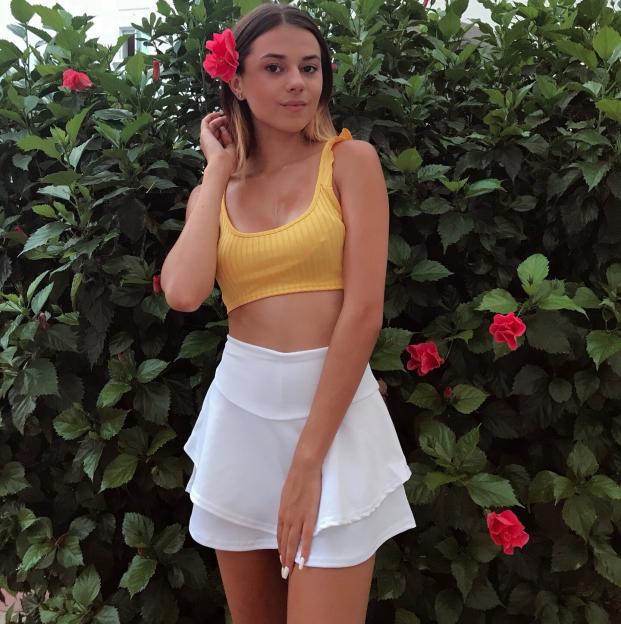 Young woman in yellow top and white skirt.