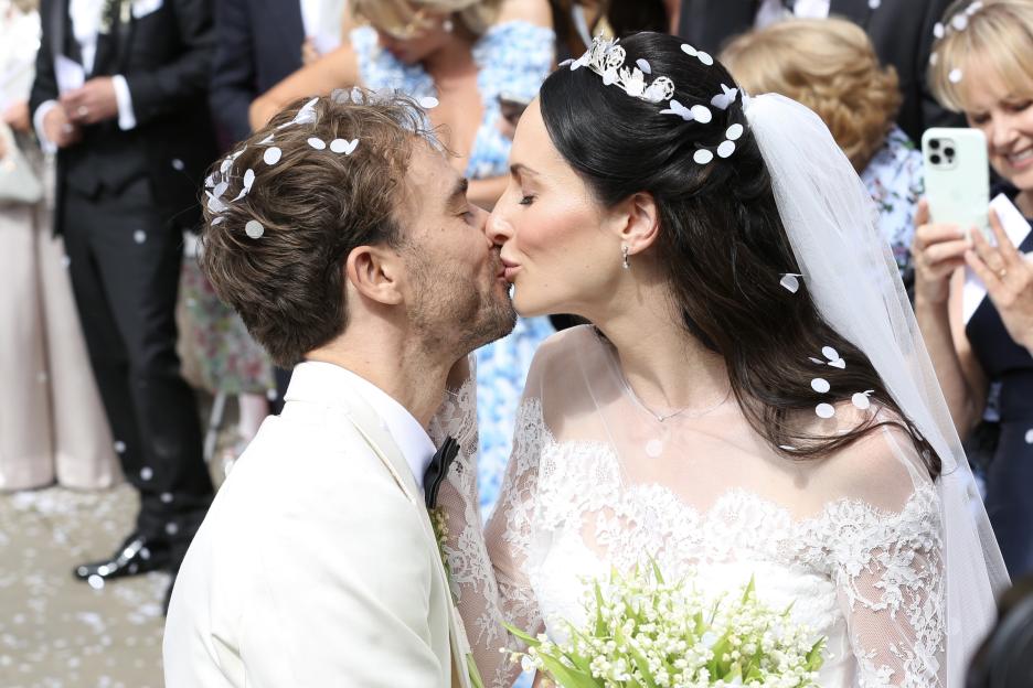 Newlyweds kissing after their wedding ceremony, confetti falling on them.