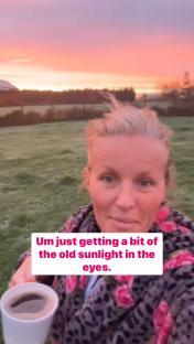 Woman holding a coffee cup at sunrise.