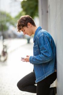 Young man in denim jacket using a smartphone.