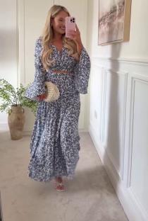 Woman in floral maxi dress and sandals taking a selfie.