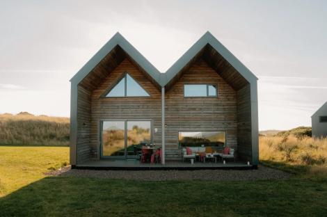 Two adjacent wooden lodges with outdoor seating areas.