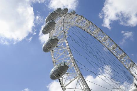 Low-angle view of the London Eye against a blue sky.