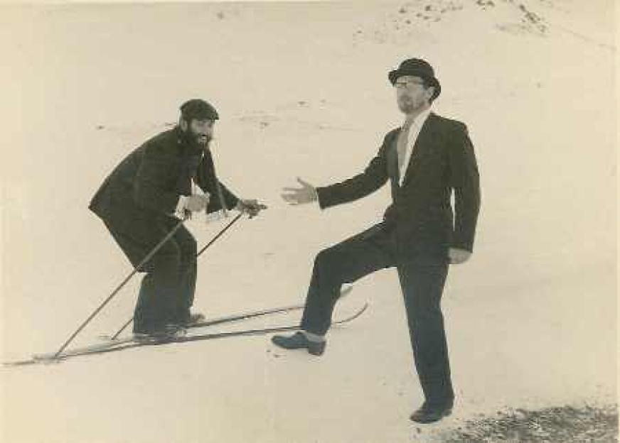 Black and white photo of two men on skis in the snow.