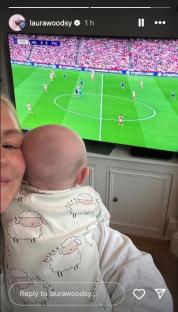 Woman holding baby while watching soccer game on TV.