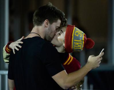 Miley Cyrus kissing Patrick Schwarzenegger at a football game.