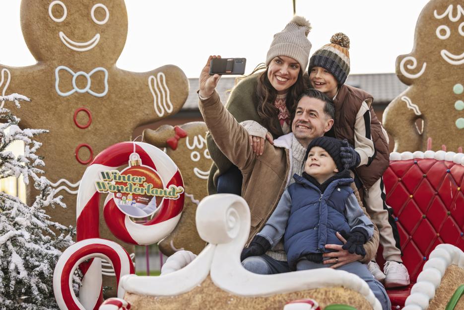 A family of four taking a selfie at a Christmas-themed holiday park.