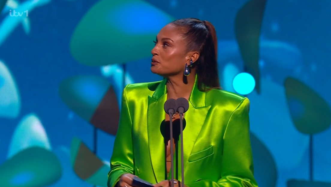 Woman in a bright green blazer accepting an award.