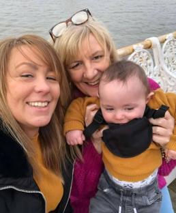 Photo of two women and a baby near water.