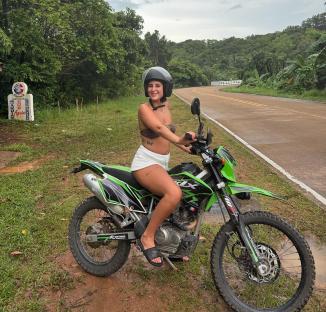 Young woman sitting on a green motorcycle in Thailand.