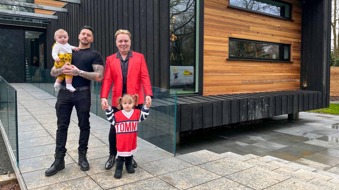 Multimillionaire dad with his two children in front of their modern home.