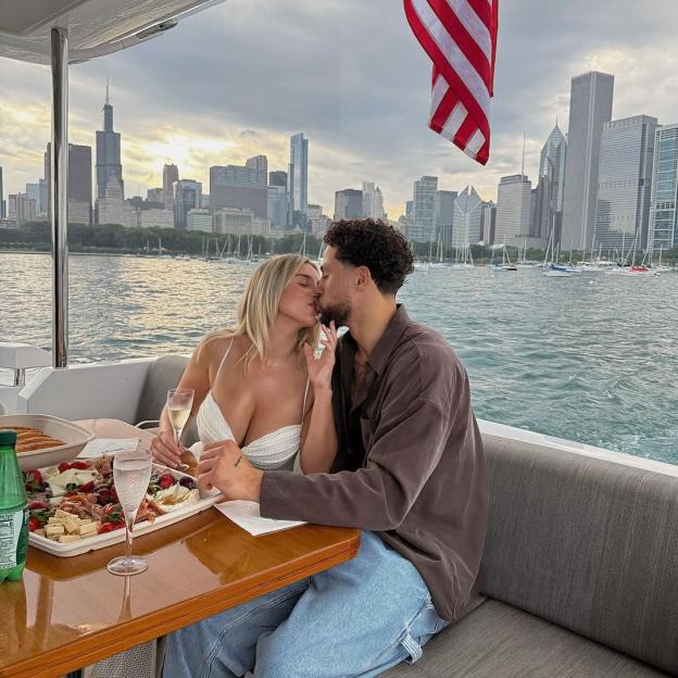 Elle Brown and her fiancé kissing on a boat with Chicago skyline in the background.