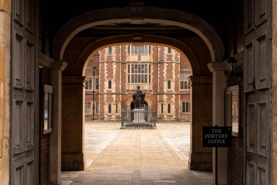 Boys in uniform race across the cobbled School Yard of Eton College.