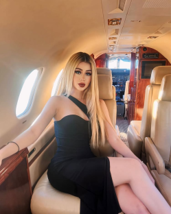 Woman in black dress sitting in private jet.