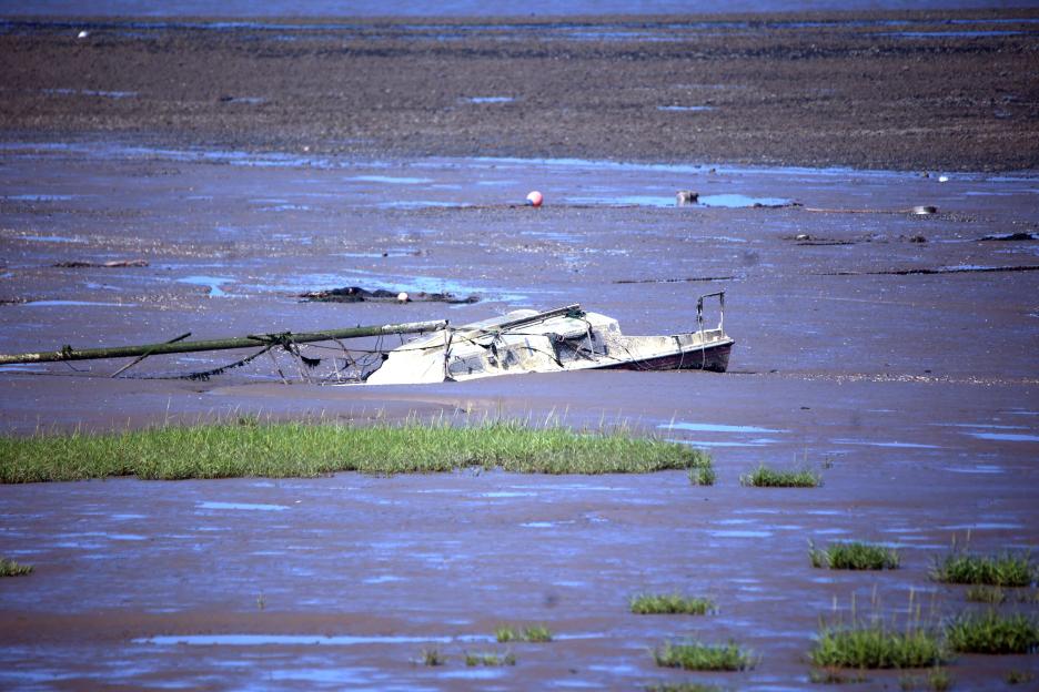 Sunken sailboat on a mudflat.