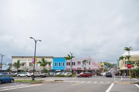 Hilo Bay street scene with shops and parked cars.