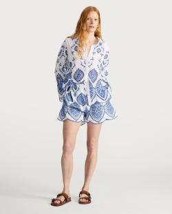 Woman wearing a blue and white embroidered shirt and shorts.