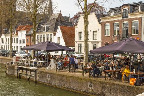 People seated at outdoor cafe tables along a canal.