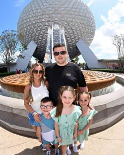 Family posing in front of Spaceship Earth at Epcot.