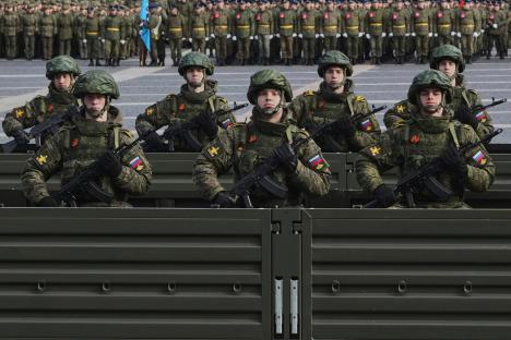 Russian soldiers with rifles in a truck during a military parade rehearsal.