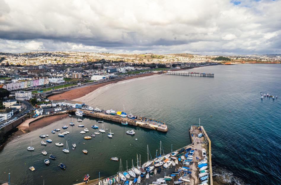 Aerial view of Paignton Harbour and South Quay with boats, the Paignton Pier, beach and town in the background, Devon, England.