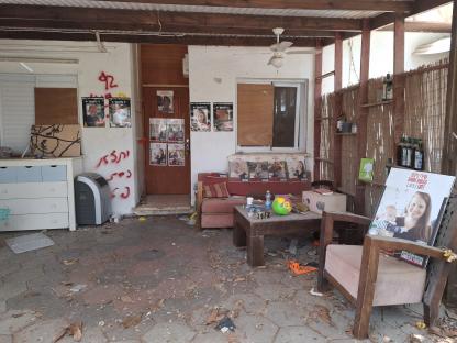 Damaged home in Kibbutz Nir Oz, Israel, with missing persons posters.