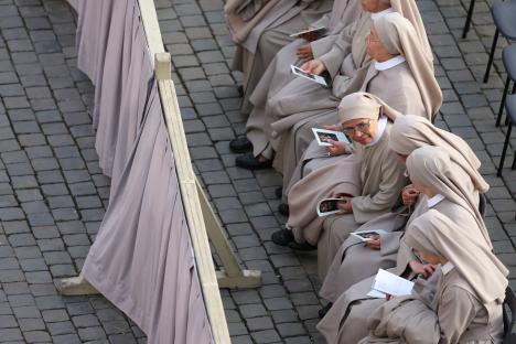 Nuns seated outdoors, holding pamphlets.