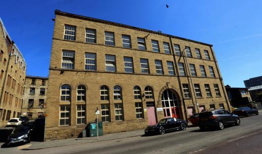 Stone building with many windows, cars parked in front.