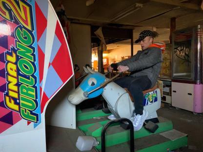Person riding a mechanical horse in an abandoned arcade.