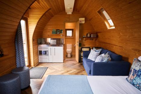 Couple walking hand-in-hand past refurbished glamping pods.