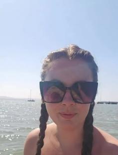 Woman in sunglasses by the water, text overlay: