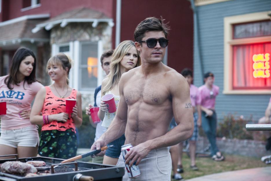 Zac Efron shirtless with a muscular physique, smiling at the camera.