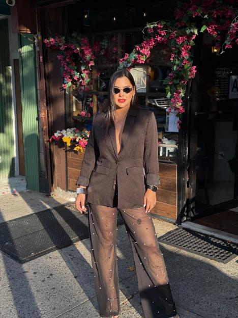 Woman in black blazer and sheer pants.